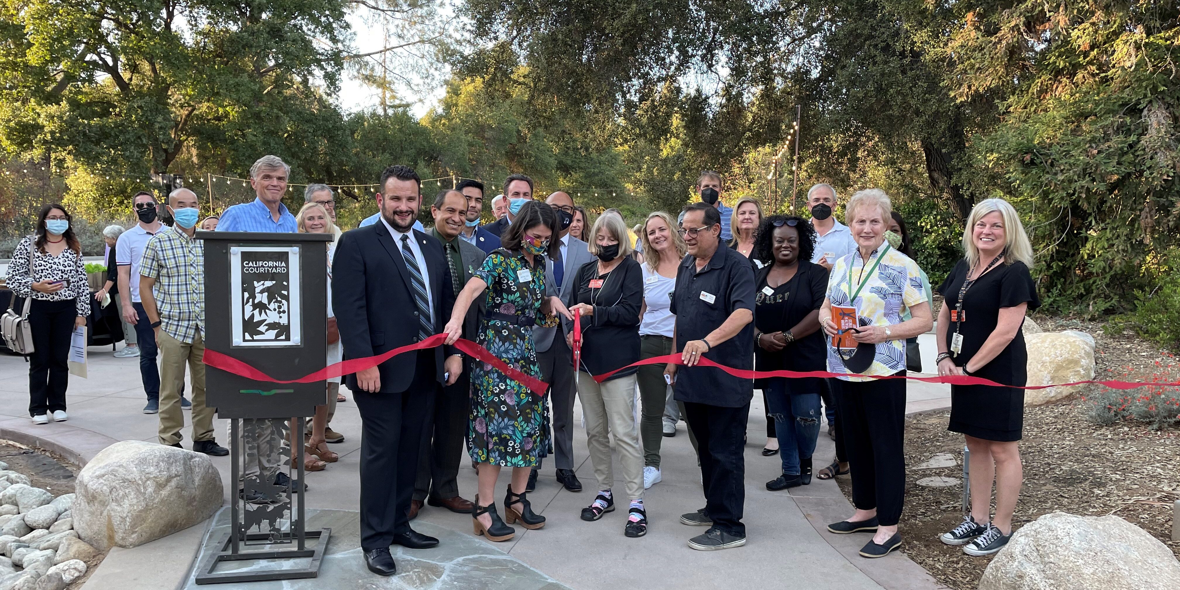 A group of elected government officials of Claremont and Claremont Chamber Members and Staff at a ribbon cutting ceremony smiling